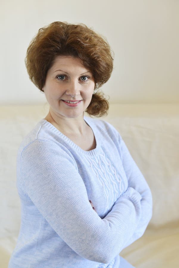 Frau in einer blauen Strickjacke, die auf einem Sofa sitzt stockfotografie Frau in einer blauen Strickjacke, die auf einem Sofa sitzt stockfotografie