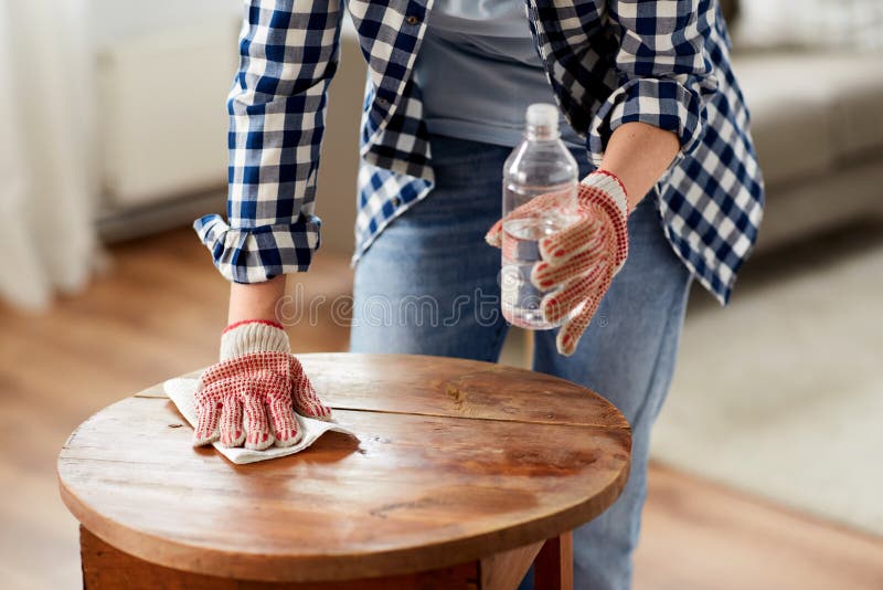 furniture renovation, diy and home improvement concept - close up of woman degreasing old round wooden table surface with solvent and paper. furniture renovation, diy and home improvement concept - close up of woman degreasing old round wooden table surface with solvent and paper