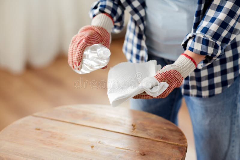 furniture renovation, diy and home improvement concept - close up of woman degreasing old round wooden table surface with solvent and paper. furniture renovation, diy and home improvement concept - close up of woman degreasing old round wooden table surface with solvent and paper