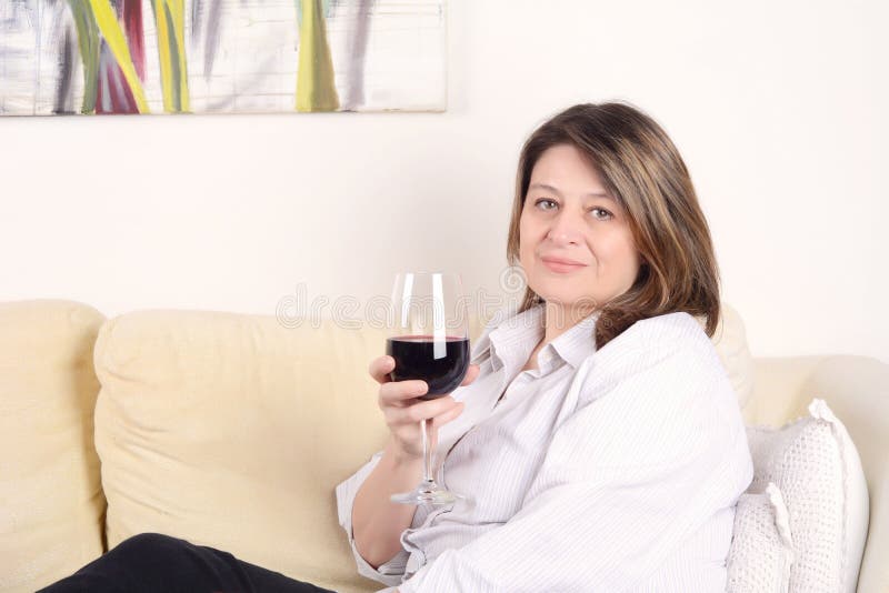Frau entspannte sich auf Sofa mit einem Glas Wein lizenzfreies stockbild Frau entspannte sich auf Sofa mit einem Glas Wein lizenzfreies stockbild