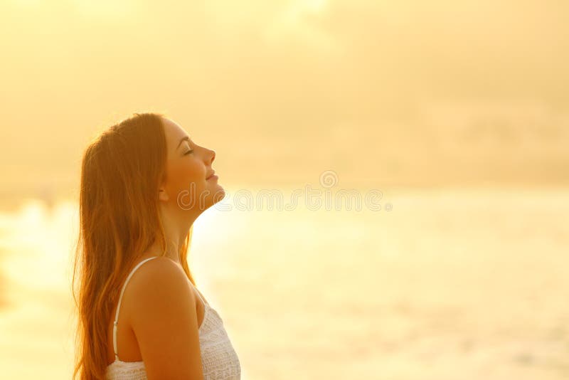 Side view portrait of woman at sunset relaxing breathing fresh air deeply on the beach. Side view portrait of woman at sunset relaxing breathing fresh air deeply on the beach