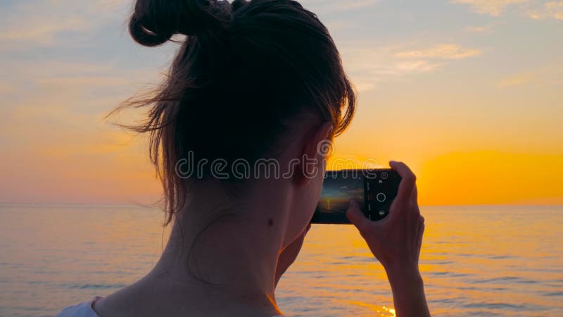 Frau fotografiert Video von Sonnenuntergang über dem Schwarzen Meer mit Smartphone