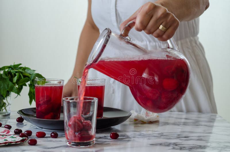 Frau füllt Preiselbeersaft im Glas lizenzfreies stockbild