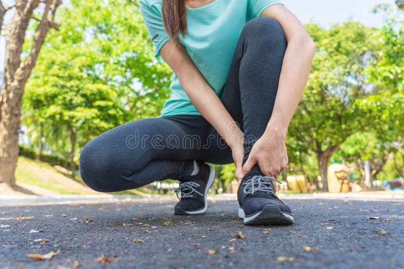 Frau hat die Schmerz in seinem Fuß beim Laufen in den Park stockbild