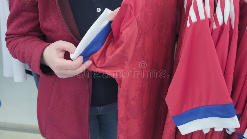 Frau im Geschäft wählt Hemd für Sport mit Druck der Flagge der Russischen Föderation
