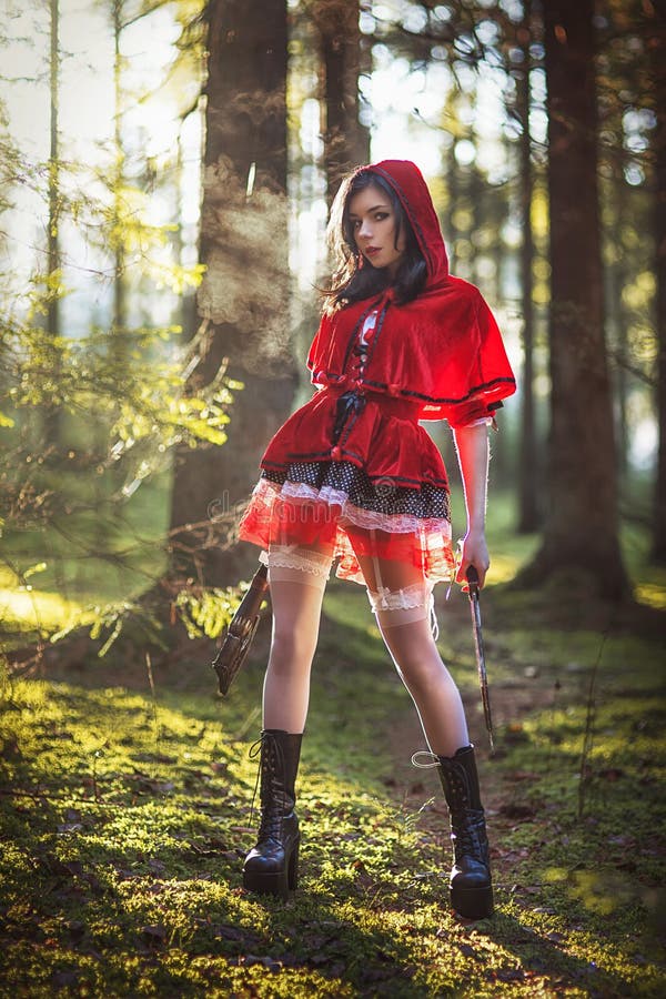 Woman in carnival costume.Sexy Little Red Riding in the woods with a gun. Woman in carnival costume.Sexy Little Red Riding in the woods with a gun