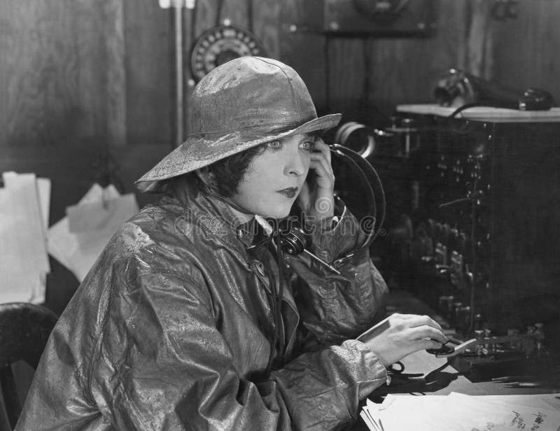 Woman in raincoat sending message in Morse code (All persons depicted are no longer living and no estate exists. Supplier grants that there will be no model release issues.). Woman in raincoat sending message in Morse code (All persons depicted are no longer living and no estate exists. Supplier grants that there will be no model release issues.)
