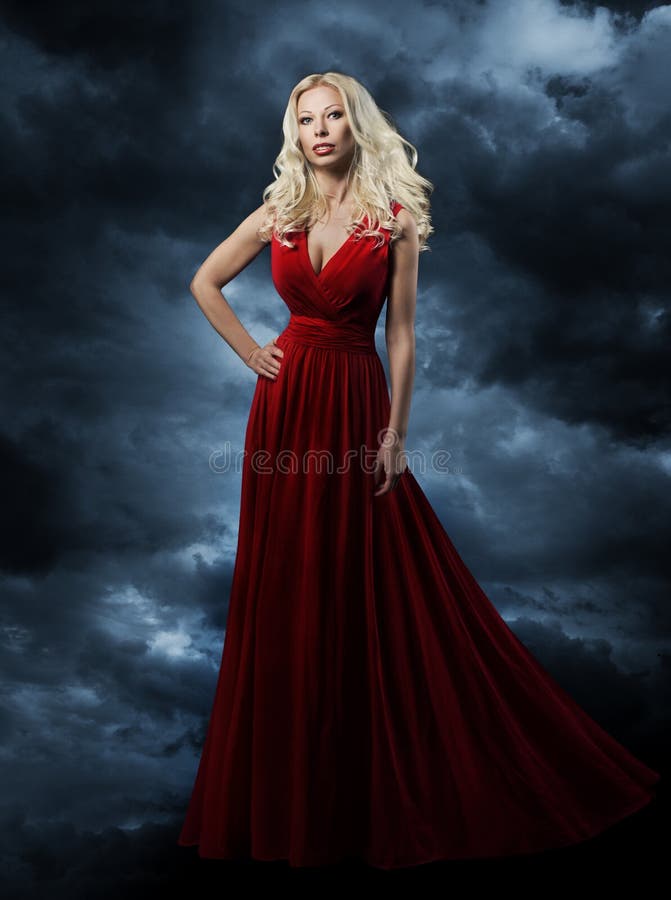 Woman in red dress, long hair blonde in fashion evening gown over sky background, hand on hip. Woman in red dress, long hair blonde in fashion evening gown over sky background, hand on hip