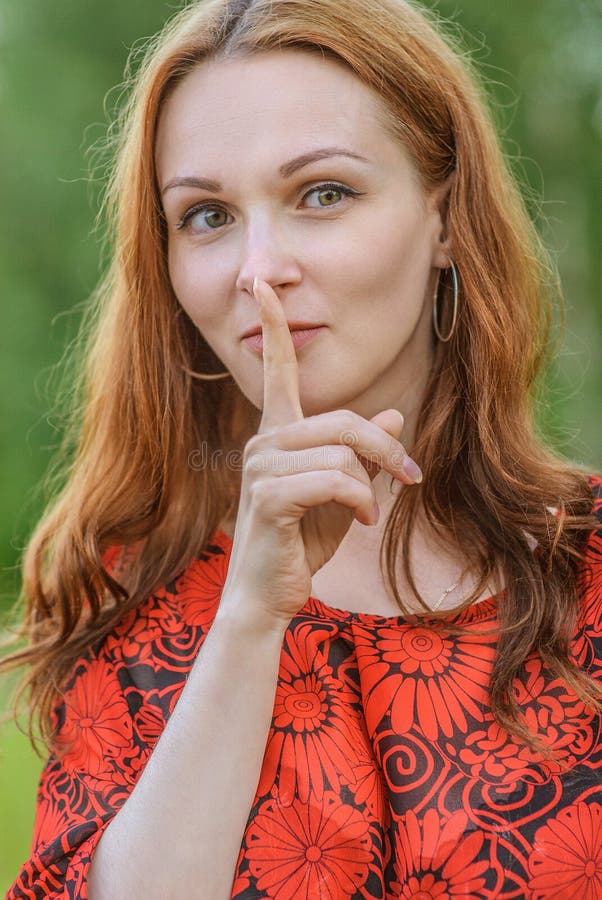 Frau im roten Kleid setzte Finger zu den Lippen lizenzfreie stockbilder Frau im roten Kleid setzte Finger zu den Lippen lizenzfreie stockbilder