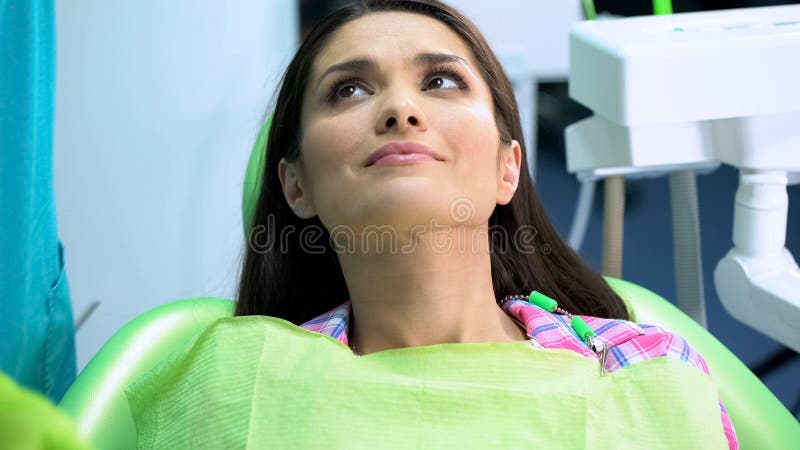 Frau im Zahnheilkundestuhl, der Doktor vor Verfahren auf Plakettenabbau betrachtet lizenzfreie stockfotografie Frau im Zahnheilkundestuhl, der Doktor vor Verfahren auf Plakettenabbau betrachtet lizenzfreie stockfotografie