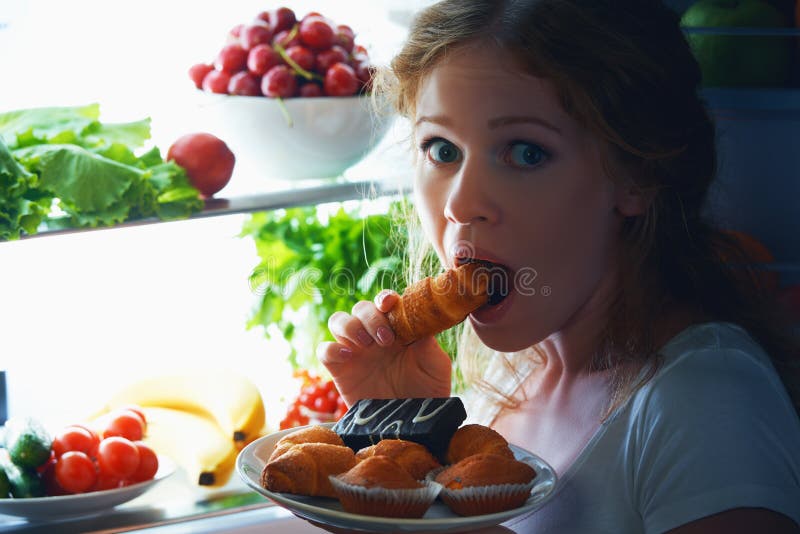 Woman eats sweets at night to sneak in a refrigerator. Woman eats sweets at night to sneak in a refrigerator