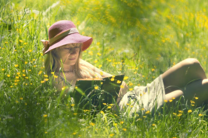 Frau liest Buch in der sonnigen Wiese