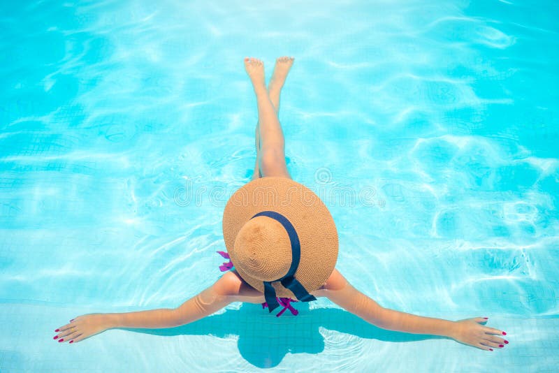 Frau mit dem braunen Hut, der im Swimmingpool mit blauem Wasser in der Sonne, Feiertagskonzept sich entspannt stockfotos Frau mit dem braunen Hut, der im Swimmingpool mit blauem Wasser in der Sonne, Feiertagskonzept sich entspannt stockfotos
