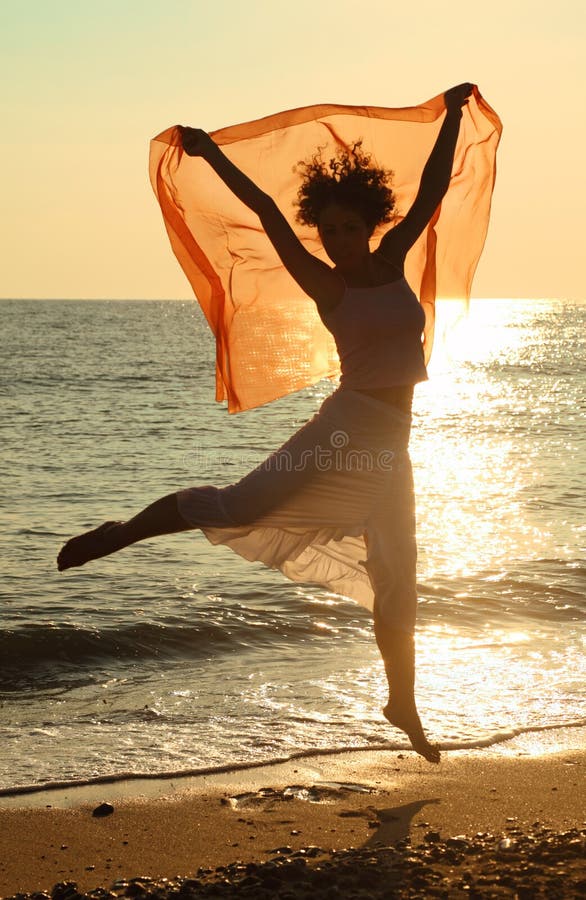 Frau mit dem roten Taschentuch, das auf Strand springt stockfoto Frau mit dem roten Taschentuch, das auf Strand springt stockfoto