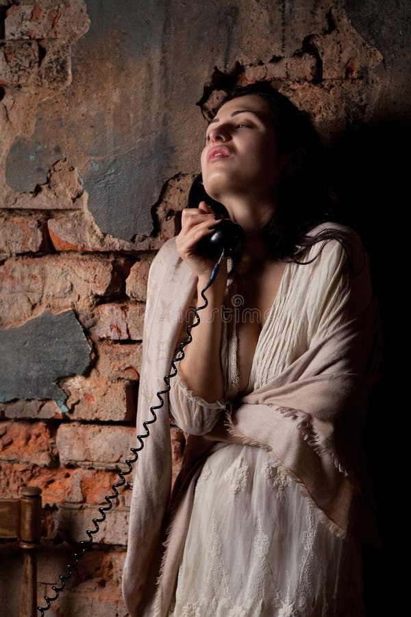 Woman with the old phone on the background of a brick wall. In a retro style. Woman with the old phone on the background of a brick wall. In a retro style