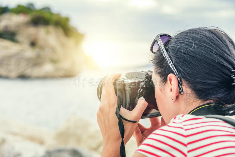 Frau mit einer Kamera den Sonnenuntergang auf der Seeküste fotografierend stockfoto Frau mit einer Kamera den Sonnenuntergang auf der Seeküste fotografierend stockfoto
