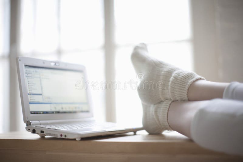 Frau mit Füßen auf Schreibtisch nahe Laptop lizenzfreie stockfotografie Frau mit Füßen auf Schreibtisch nahe Laptop lizenzfreie stockfotografie