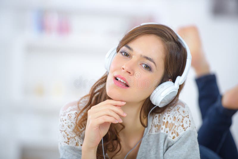 Frau mit Kopfhörer im Bett liegend und Musik hören stockfoto