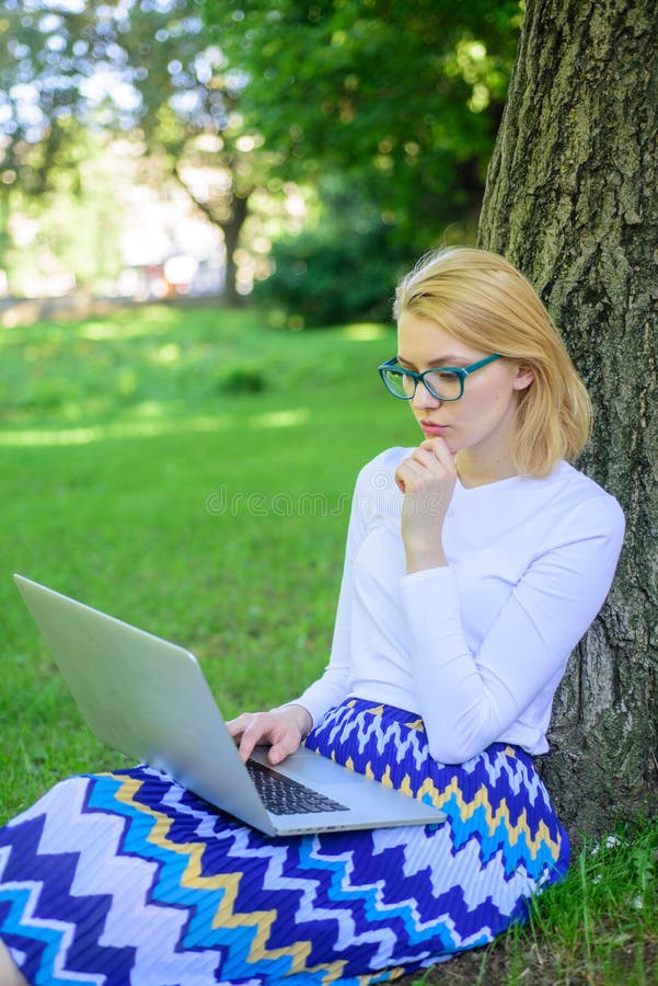 Woman with laptop works outdoor, park background. Girl sit grass lean tree trunk with notebook. Wi fi network connection free access. Surfing internet in nature. Lady freelancer working in park. Woman with laptop works outdoor, park background. Girl sit grass lean tree trunk with notebook. Wi fi network connection free access. Surfing internet in nature. Lady freelancer working in park.