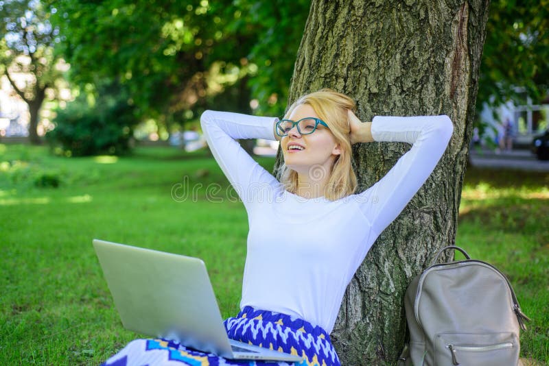 Woman with laptop works outdoor, park background. Taking advantages of freelance. Girl sit grass lean tree trunk with notebook. Wi fi network connection free access. Lady freelancer working in park. Woman with laptop works outdoor, park background. Taking advantages of freelance. Girl sit grass lean tree trunk with notebook. Wi fi network connection free access. Lady freelancer working in park.