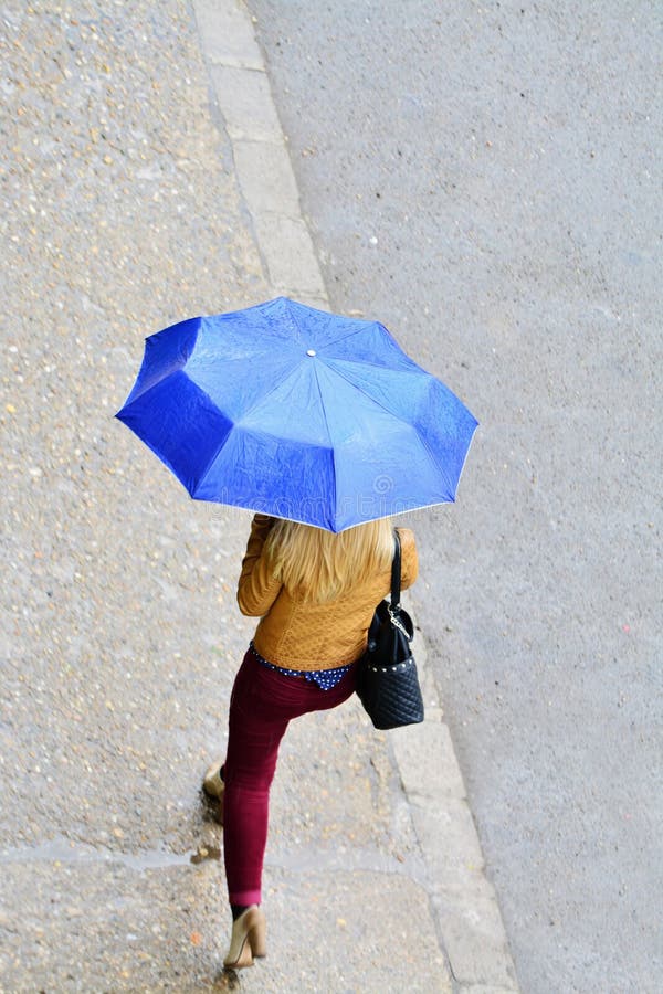 Frau mit Regenschirm gehend in den Regen stockbild Frau mit Regenschirm gehend in den Regen stockbild