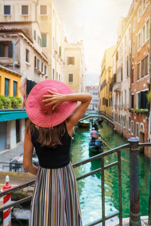 Frau mit rotem sunhat genießt die Ansicht zu einem Kanal in Venedig, Italien