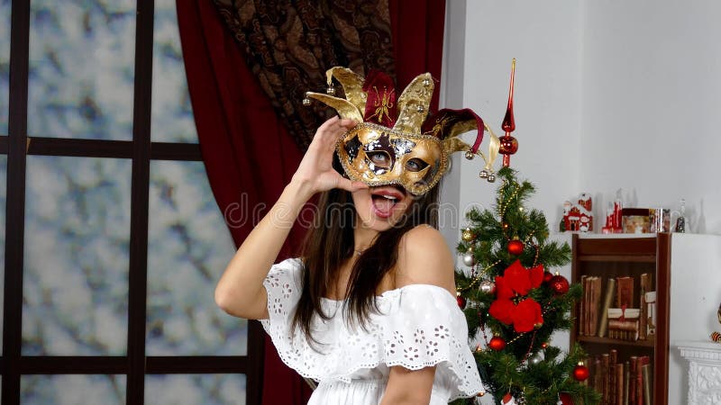Frau mit venetianischer Maske nahe durch Weihnachtsbaum