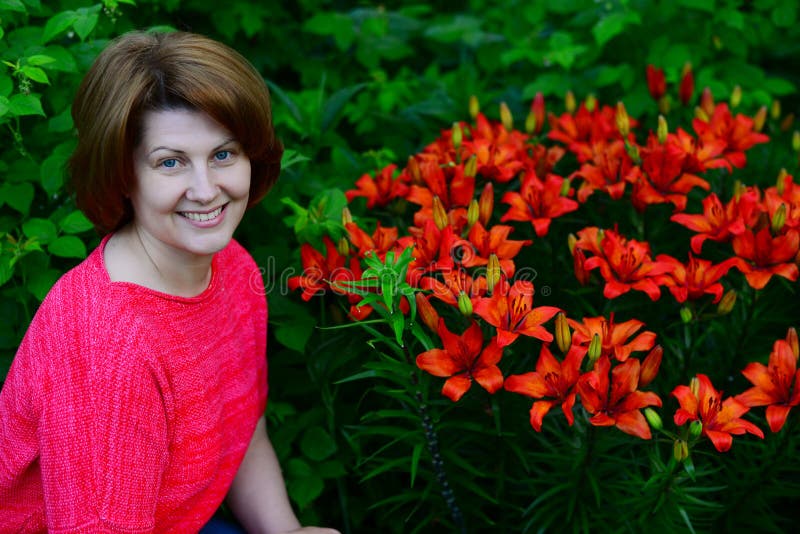 Frau nahe Blumenbeet mit orange Lilien stockbild Frau nahe Blumenbeet mit orange Lilien stockbild