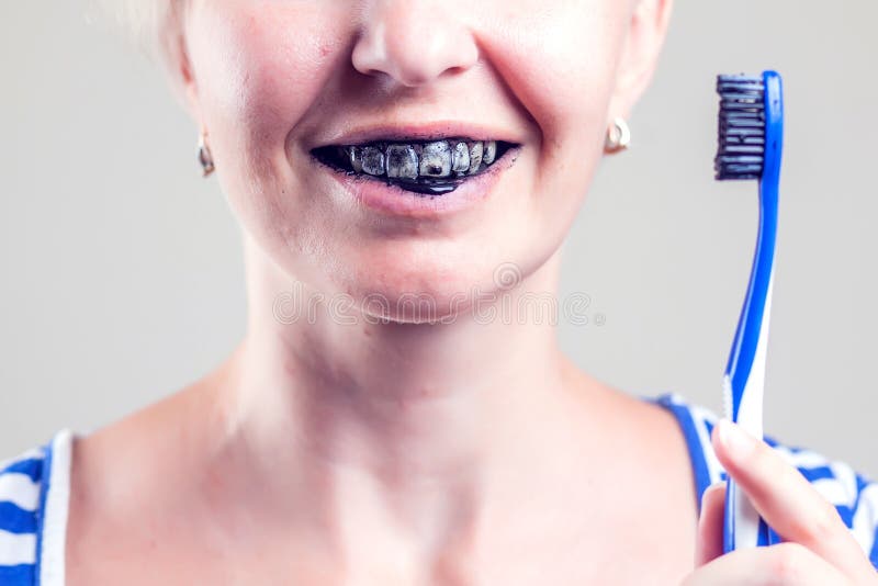 Frau reinigt ihre Zähne mit Kohlezahnpaste Konzept 'Menschen und Gesundheit'