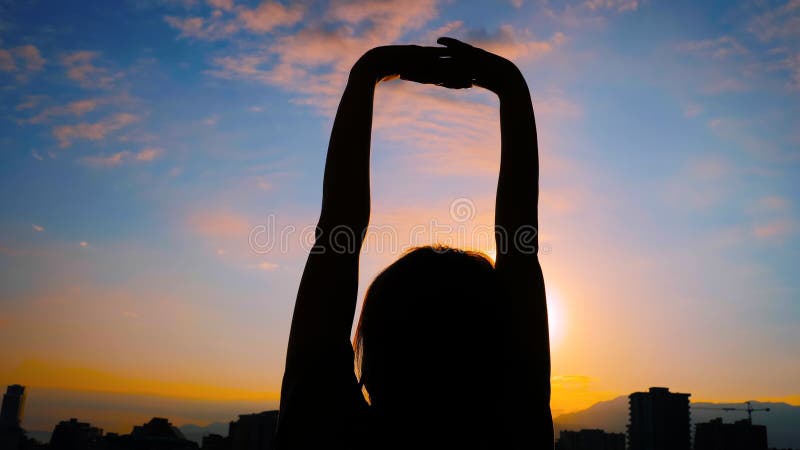 Frau Silhouette streckt Arme gegen den Sonnenaufgang hoch