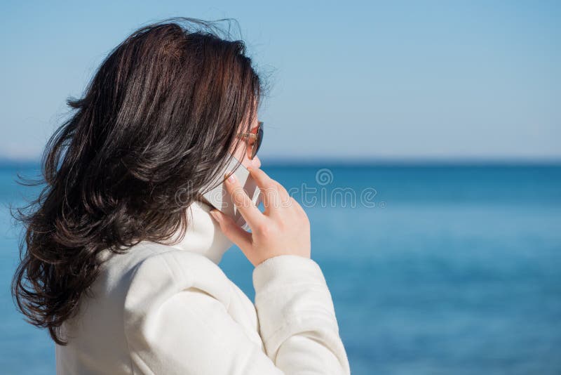 Frau spricht durch Handy an der Küste