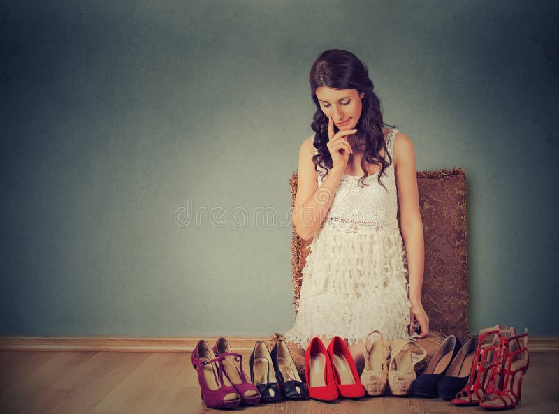 Woman making decisions picking up the right pair of high heel shoes. Woman making decisions picking up the right pair of high heel shoes