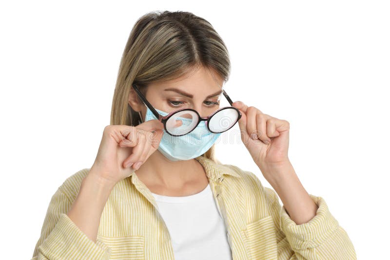 Frau, welche die nebeligen Gläser, verursacht durch das Tragen der Wegwerfmaske auf weißem Hintergrund abwischt. Schutzmaßnahme wä
