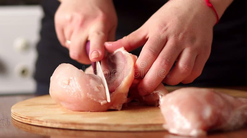 Frau übergibt den Chef, der rohe Hühnerfleischbrust schneidet