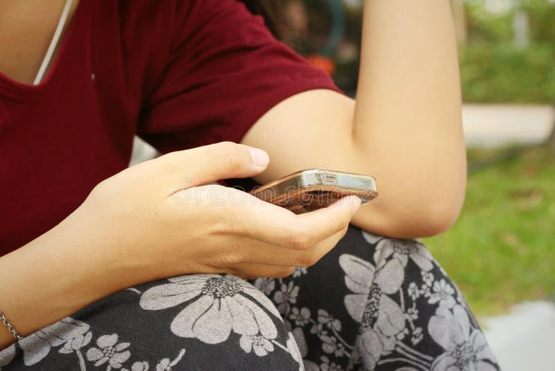 Frauen benutzen ein Telefon am Park