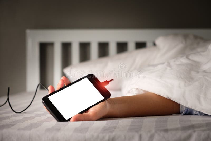 Frauen benutzen einen Handy beim Aufladen der Batterie lizenzfreie stockfotografie Frauen benutzen einen Handy beim Aufladen der Batterie lizenzfreie stockfotografie