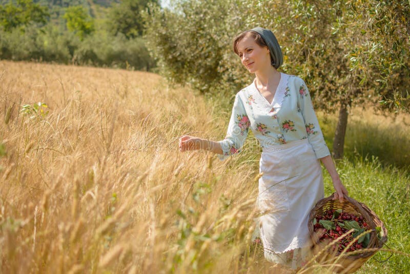 Frauen in den 40er Jahren gehen in der italienischen Landschaft, neben einem Weizenfeld, mit einem Kirschkorb stockbilder Frauen in den 40er Jahren gehen in der italienischen Landschaft, neben einem Weizenfeld, mit einem Kirschkorb stockbilder