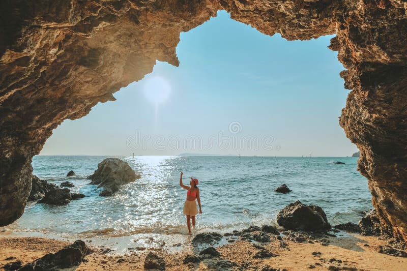Frauen, die auf einem Felsen am Höhleneingang stehen, schauen auf das Meer und die schöne Aussicht. bei Sonnenuntergang romantisch lizenzfreie stockfotos