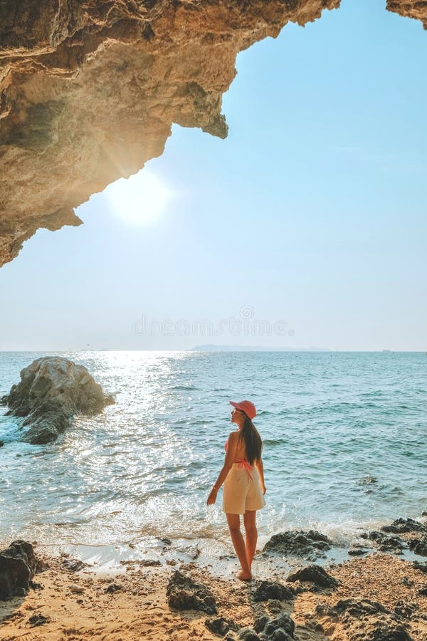 Frauen, die auf einem Felsen am Höhleneingang stehen, schauen auf das Meer und die schöne Aussicht. bei Sonnenuntergang romantisch lizenzfreie stockfotos