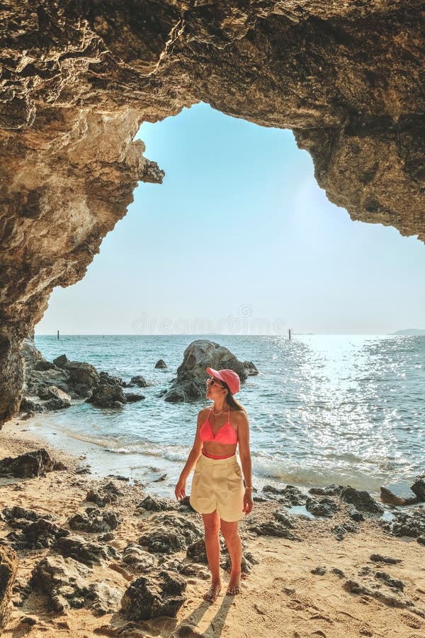 Frauen, die auf einem Felsen am Höhleneingang stehen, schauen auf das Meer und die schöne Aussicht. bei Sonnenuntergang romantisch lizenzfreie stockfotos