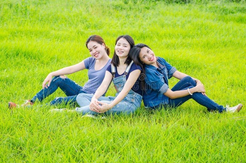 Frauen, die in der Wiese und im Lächeln sitzen stockbild Frauen, die in der Wiese und im Lächeln sitzen stockbild