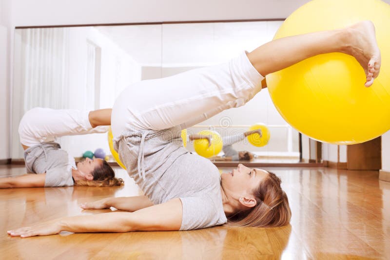 Frauen, die Eignungsübungen mit Ball machen lizenzfreie stockfotografie Frauen, die Eignungsübungen mit Ball machen lizenzfreie stockfotografie
