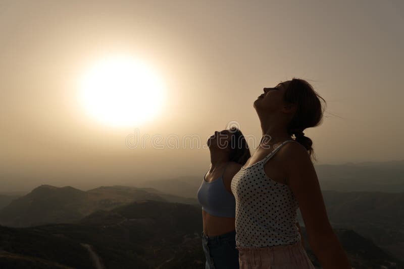 Side view portrait of two women silhouette breathing fresh air together at sunset. Side view portrait of two women silhouette breathing fresh air together at sunset