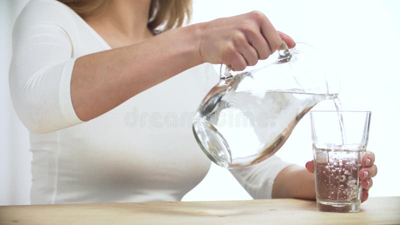 Frauen-strömendes Wasser in Glas von der Krug-Nahaufnahme