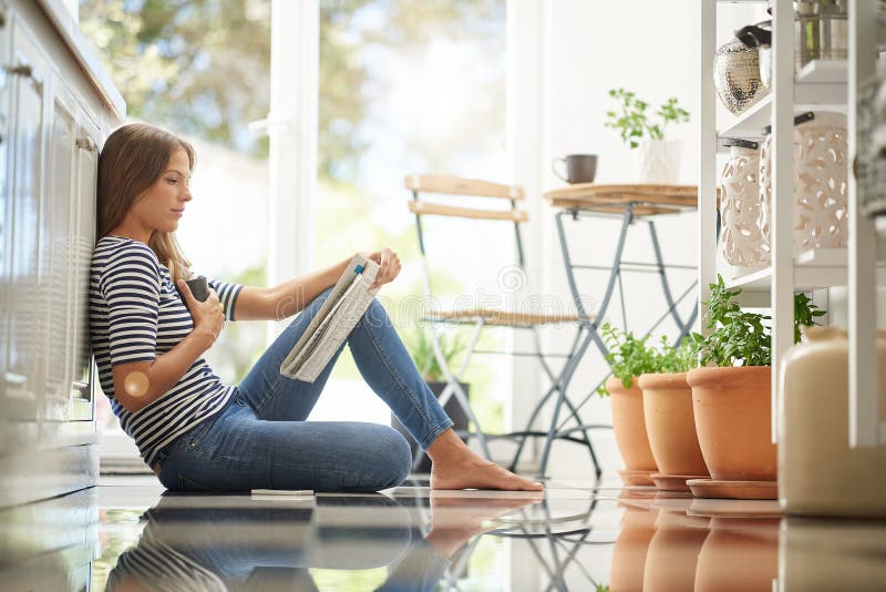 Frauen in Zeitung und zu Hause auf Küchenboden mit nachdenklichen globalen Schlagzeilen und Lesen mit Kaffee. Presse und Person lizenzfreie stockbilder