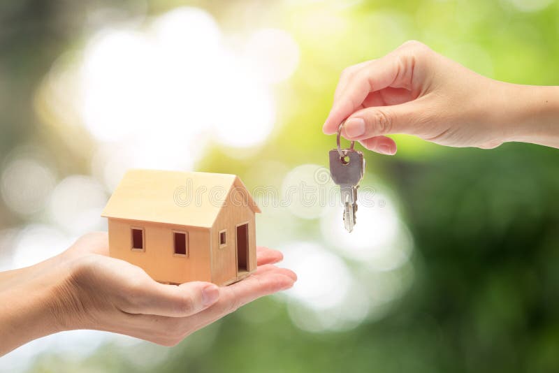 Women hand holding a model home and a key,Buying a new house concept. Women hand holding a model home and a key,Buying a new house concept