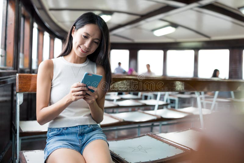 Frauenblick auf den Handy und die nehmen Fähre in Hong Kong lizenzfreies stockfoto Frauenblick auf den Handy und die nehmen Fähre in Hong Kong lizenzfreies stockfoto