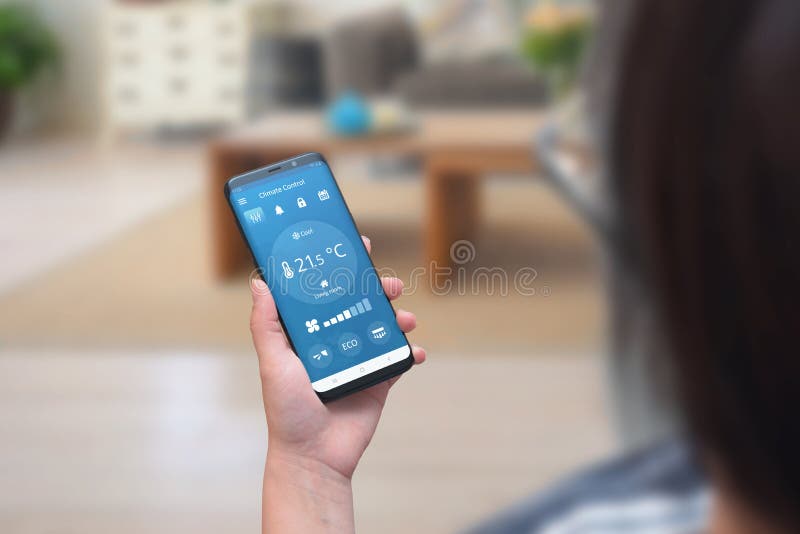 Frauengebrauchs-Klimaregelung App an einem Telefon im Wohnzimmer, zum von Temperatur und von Belüftung zu justieren lizenzfreie stockfotos Frauengebrauchs-Klimaregelung App an einem Telefon im Wohnzimmer, zum von Temperatur und von Belüftung zu justieren lizenzfreie stockfotos