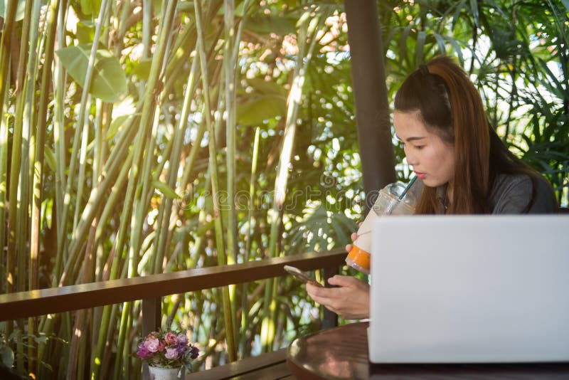 Frauengriffhandy und trinkendes Eistee in der Kaffeestube, La stockbilder Frauengriffhandy und trinkendes Eistee in der Kaffeestube, La stockbilder