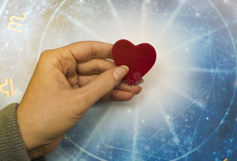 Frauenhand, die ein rotes Herz über blauem Horoskop wie Astrologie-, Tierkreis- und Liebeskonzept hält lizenzfreie stockfotos Frauenhand, die ein rotes Herz über blauem Horoskop wie Astrologie-, Tierkreis- und Liebeskonzept hält lizenzfreie stockfotos